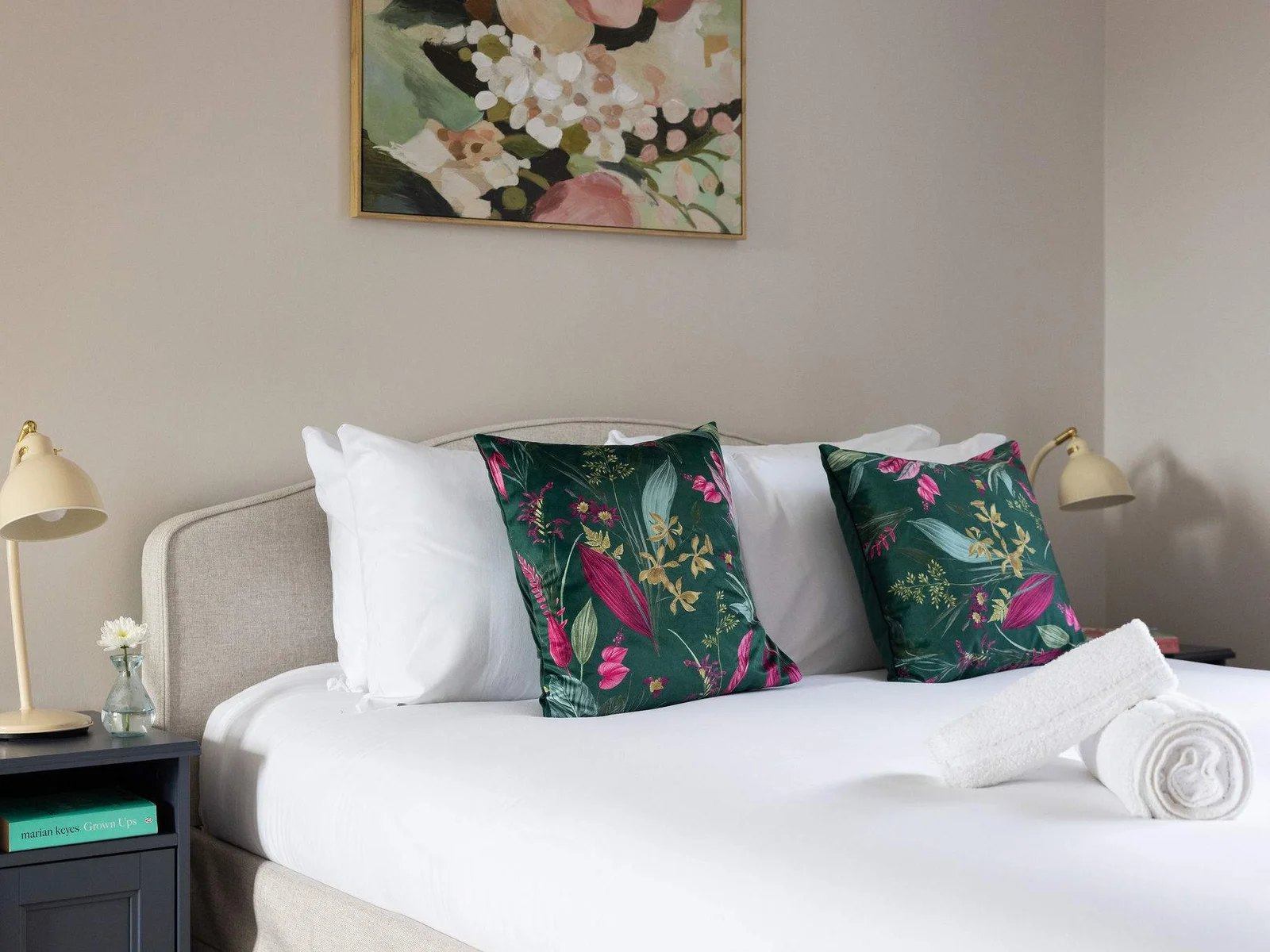 A calm and inviting double bedroom with crisp white linen, soft botanical touches and thoughtful bedside lighting — perfect for a restful night.