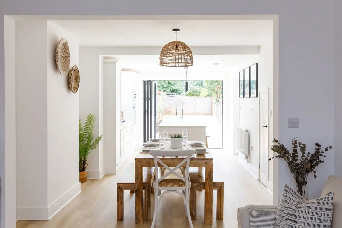 A large wooden dining table with bench seating for up to 8 guests sits between the kitchen and living room.