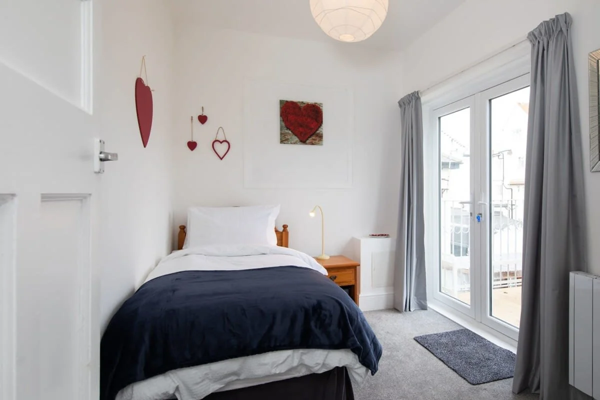 Bedroom two with a single bed and access to the private balcony via the double doors