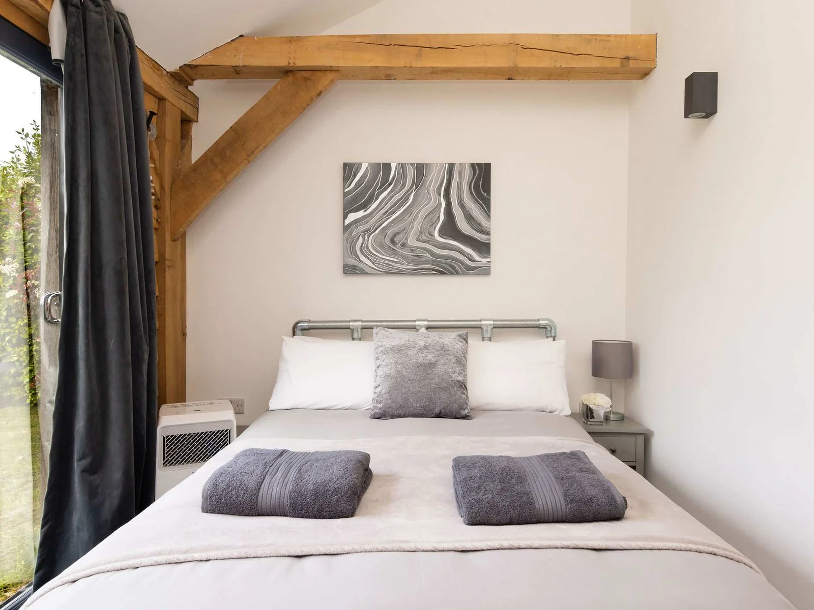 Wake up to nature in this serene double bedroom featuring beautiful exposed wooden beams.