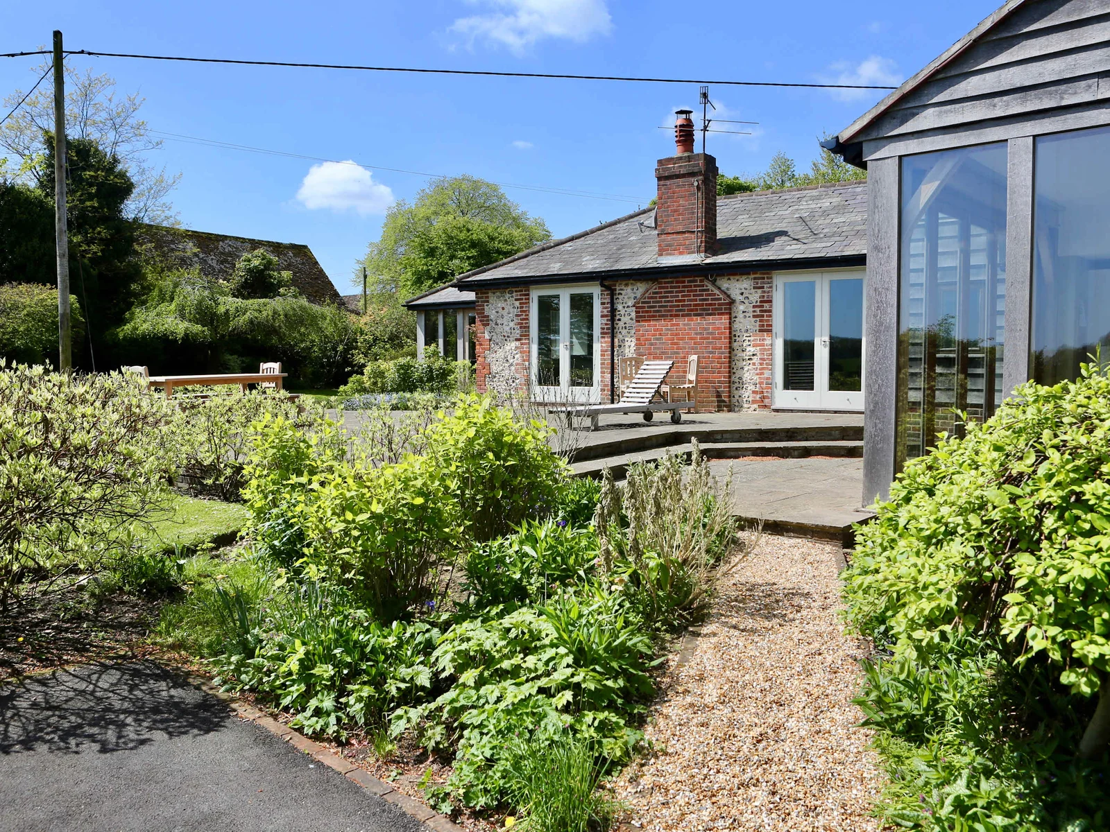 The patio from the garden showing the corner of the kitchen and doors from the lounge and master bedroom