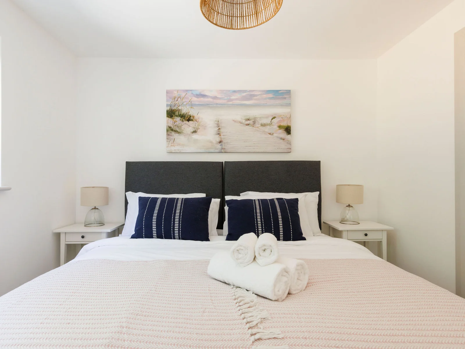 Relax in our serene bedroom with plush bedding and beach-inspired decor
