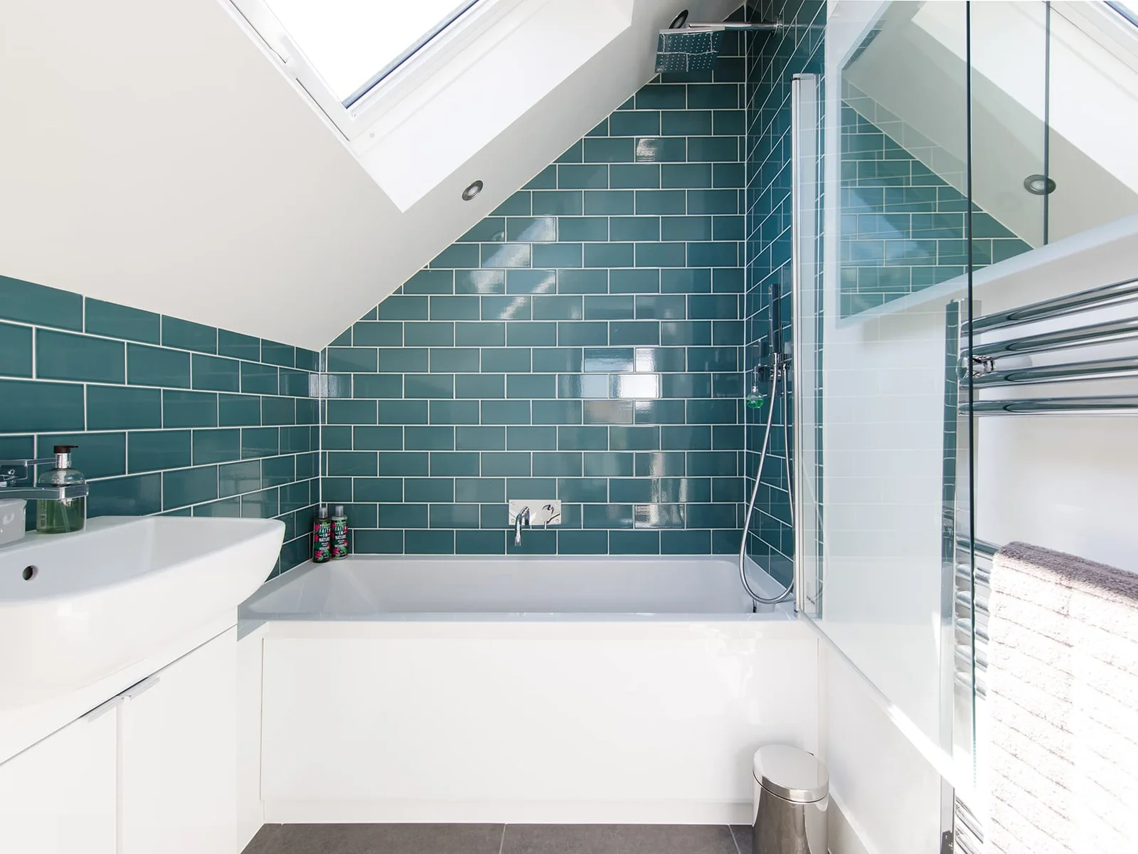 The en-suite bathroom is decorated with marine green tiles and modern fixtures.