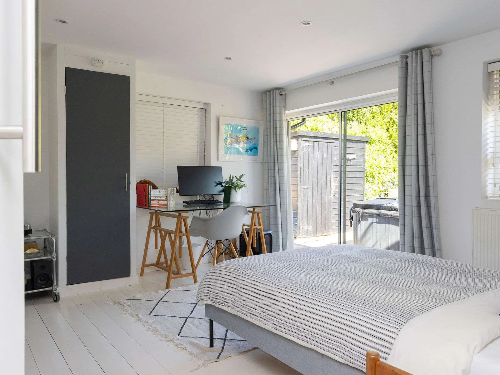 A spacious garden-facing bedroom with desk space and direct outside access