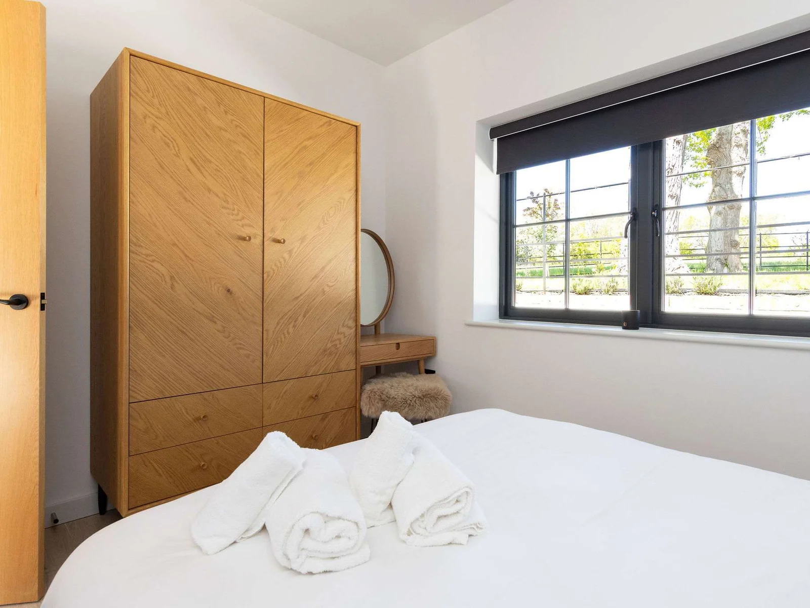 Store luggage easily in the serene bedroom, featuring warm wood finishes and soft morning light.
