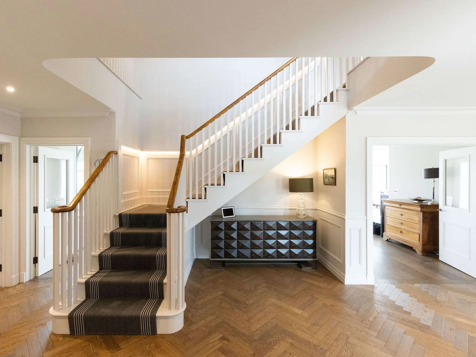 Elegant hallway with feature staircase and parquet flooring