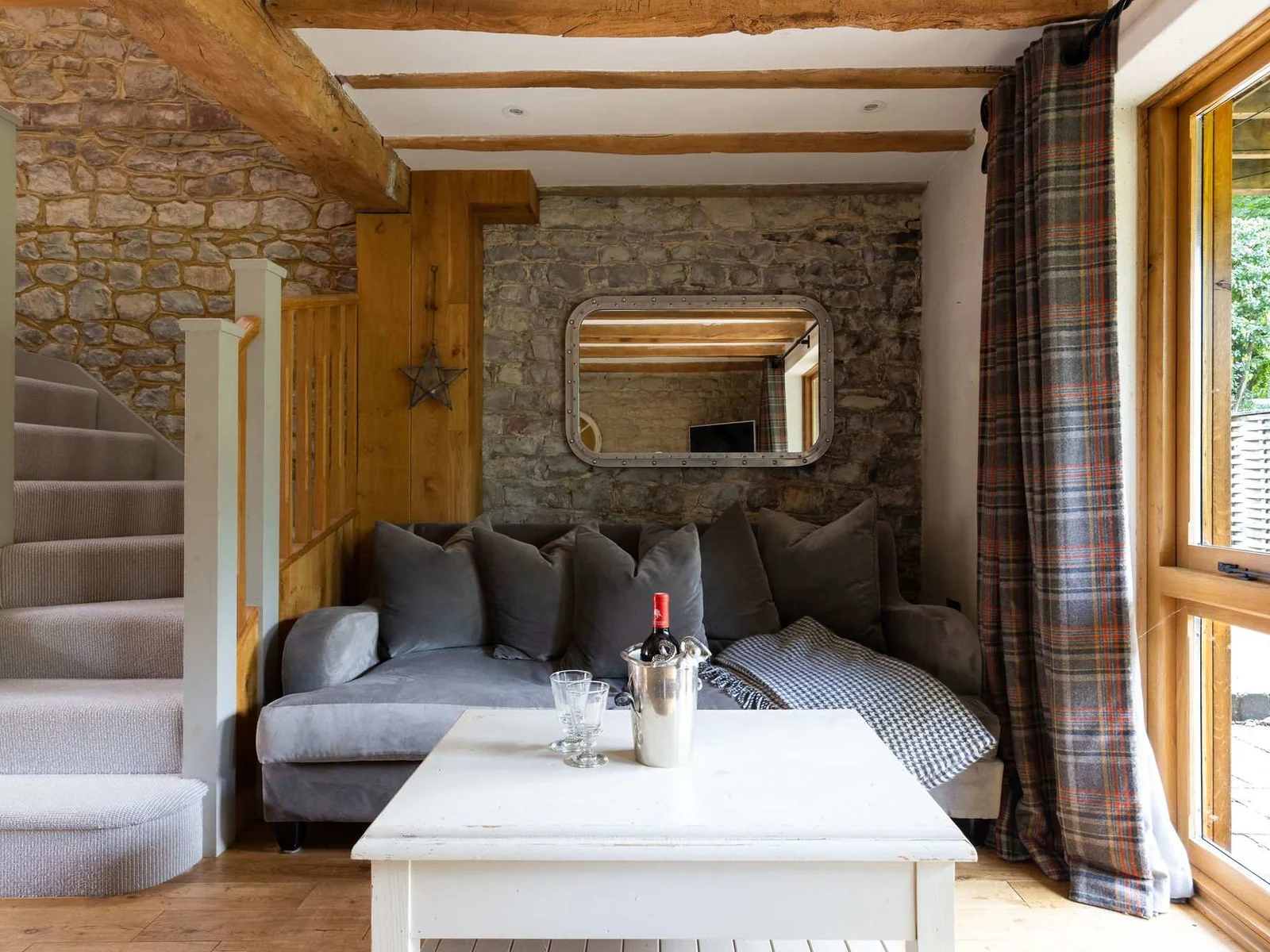 A relaxed lounge corner with soft seating, original stonework and garden views.