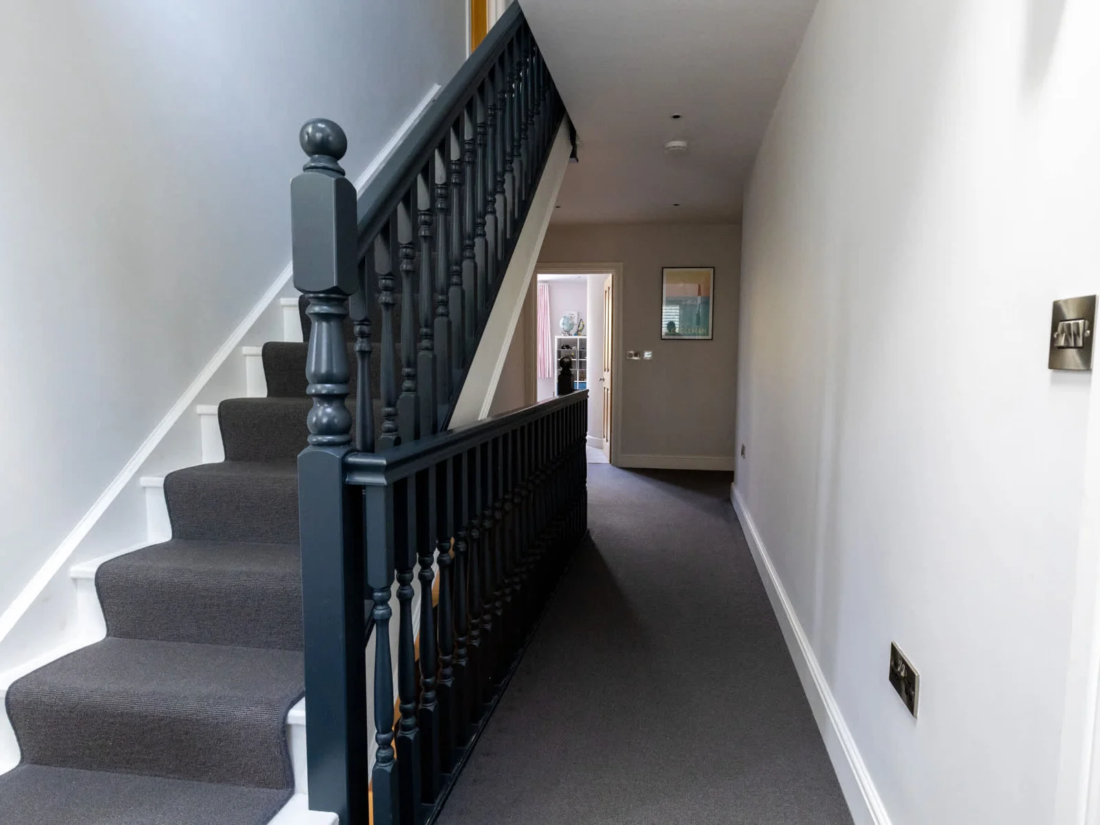 Carpeted landing with staircase and bright hallway connecting the home’s upper bedrooms.