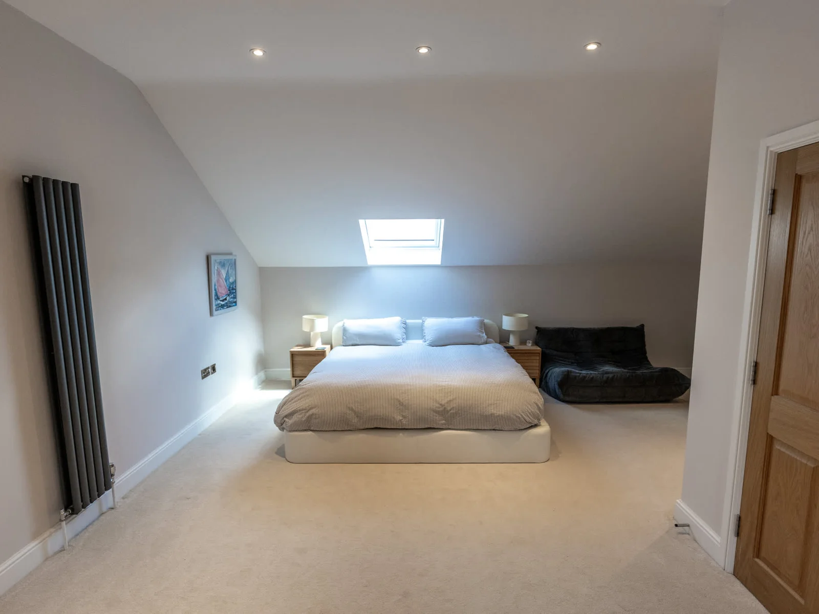 Spacious loft bedroom with skylight, king bed and cosy seating area.