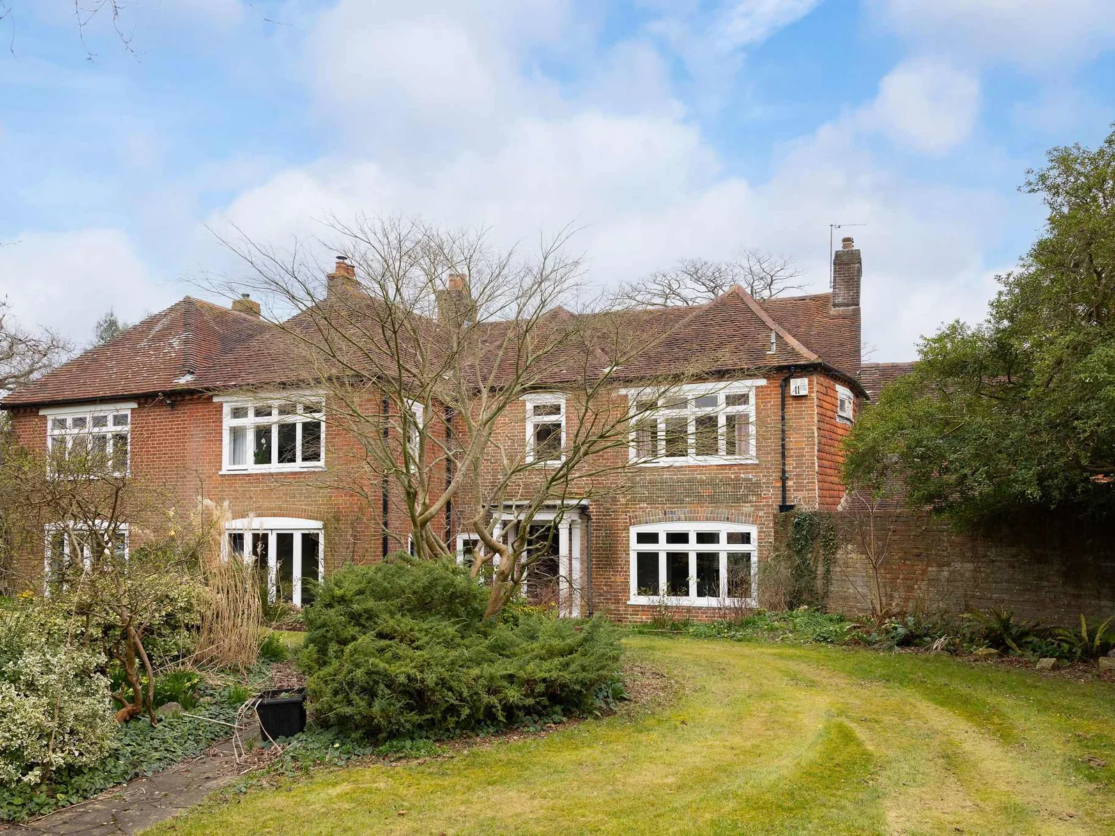 The rear garden features a spacious lawn and a classic period facade