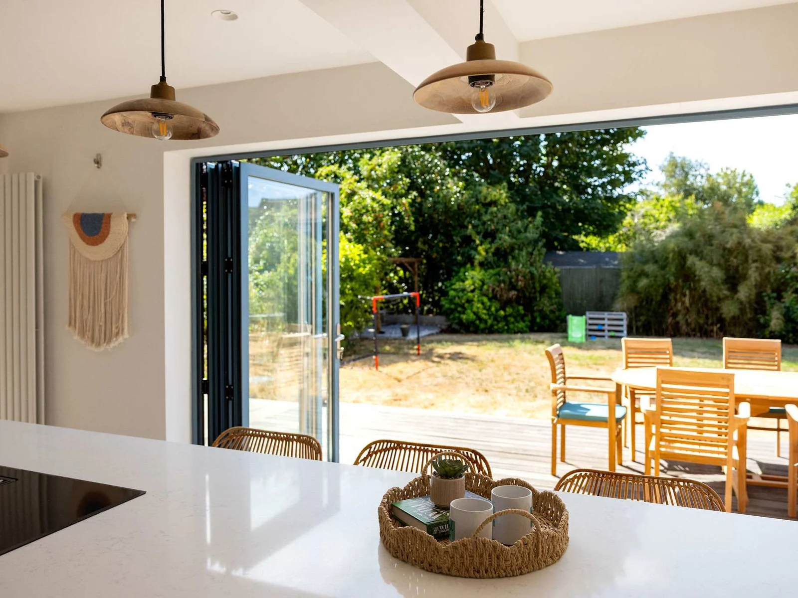 Light-filled kitchen with wide bi-fold doors opening straight onto the outdoor dining terrace and garden, creating a beautiful sense of space and effortless indoor-outdoor living.