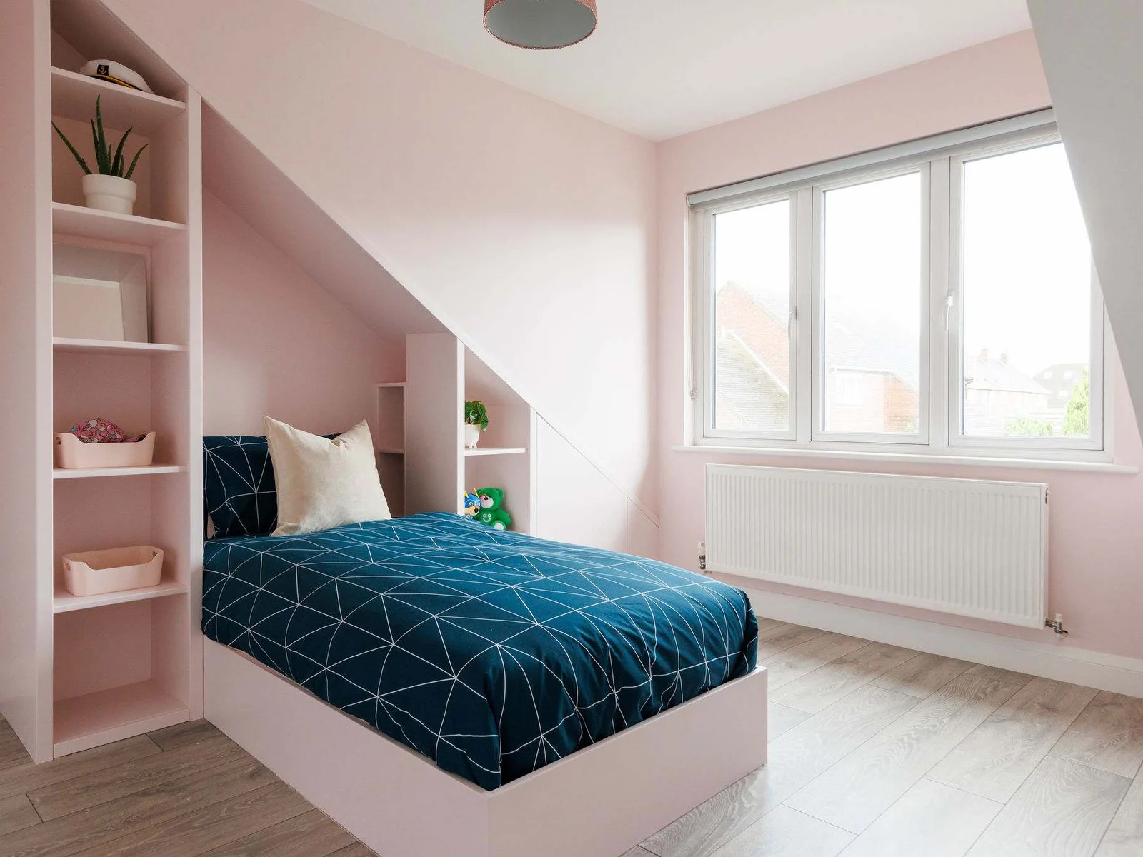 A single bedroom decorated in pale pink, with shelving for your belongings.