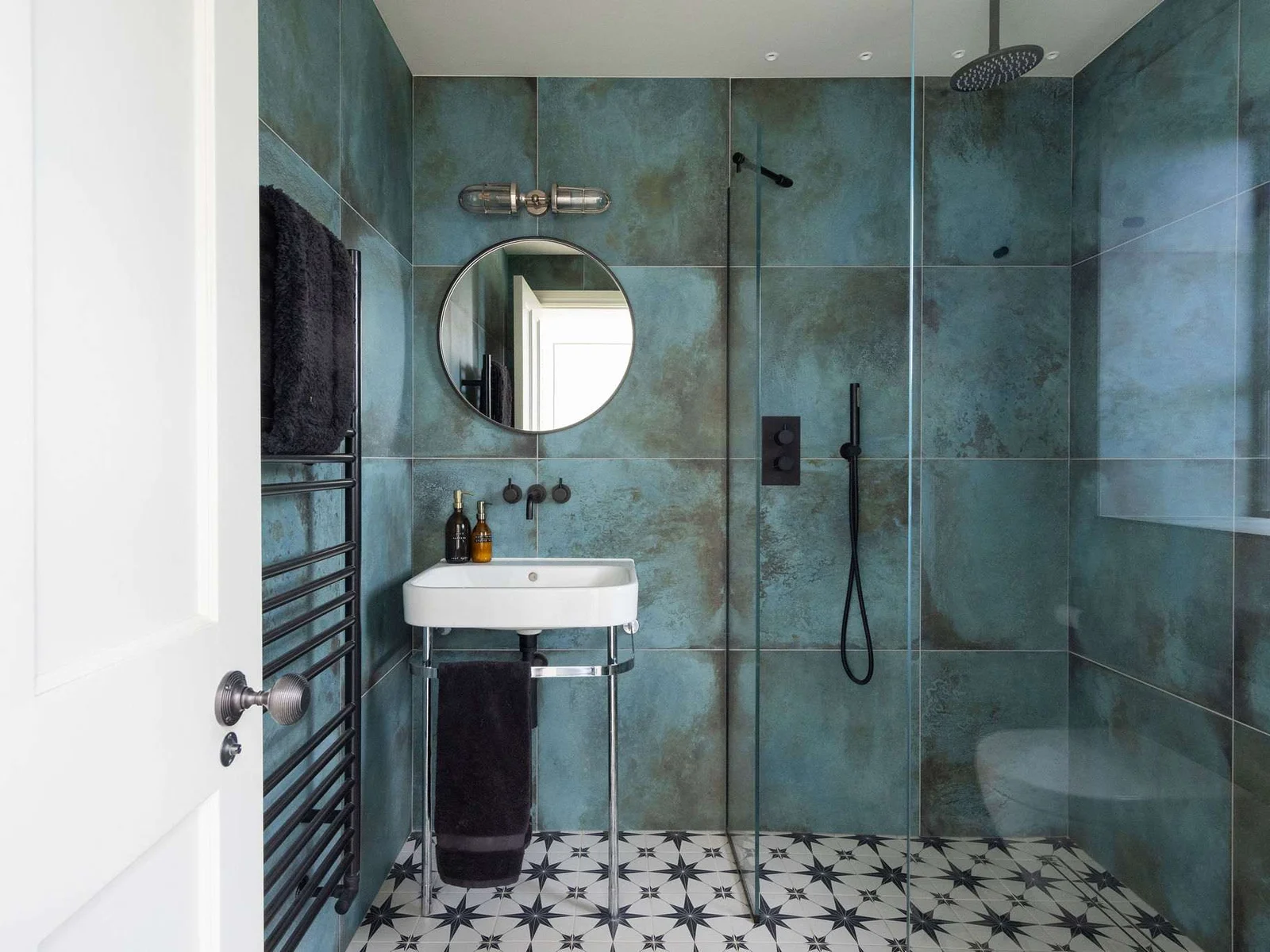 Bold teal-tiled shower room with patterned flooring, rainfall shower, and striking modern design.
