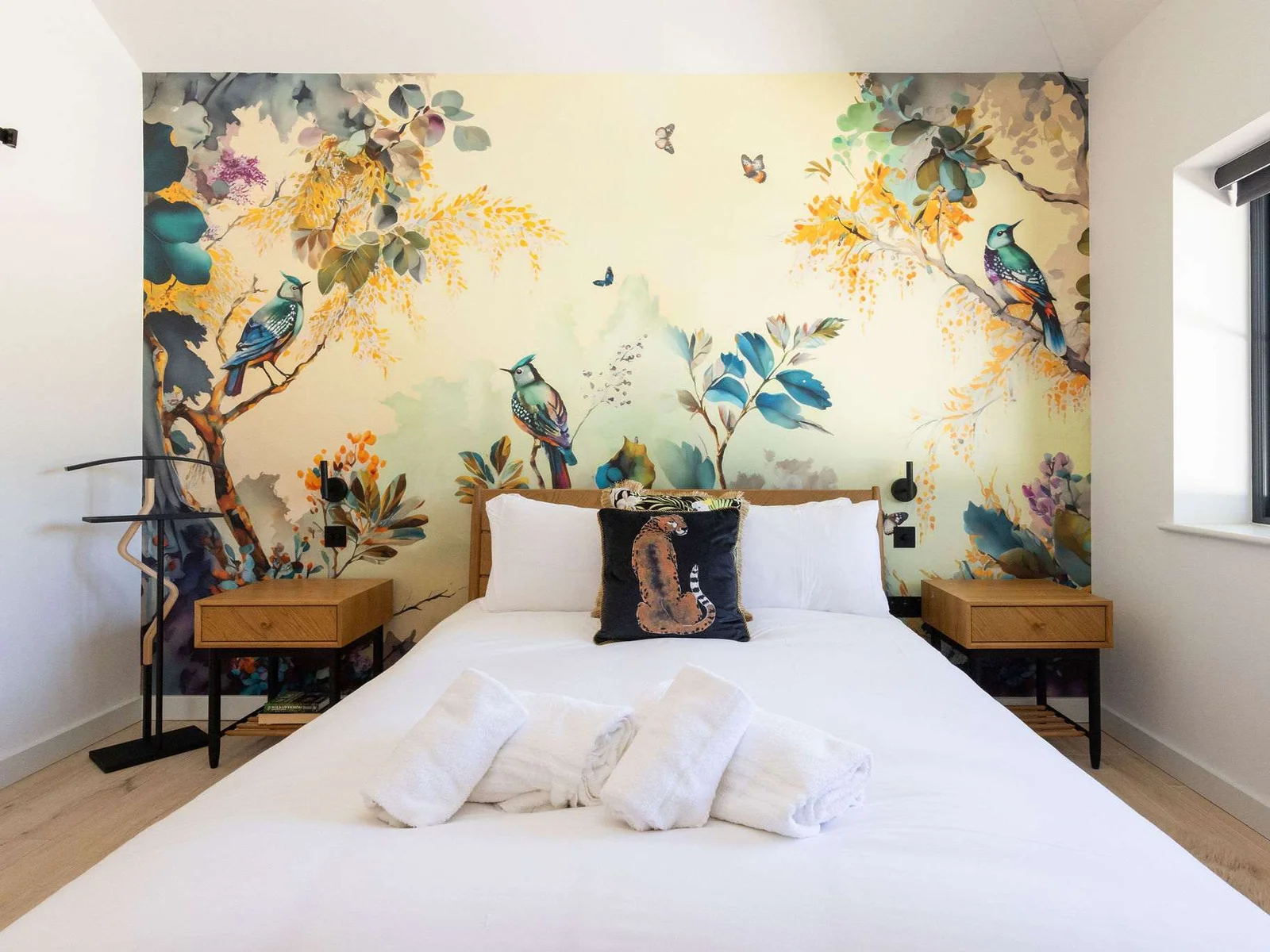 Drift into a restful king bedroom with playful wallpaper, soft linens, and peaceful countryside style.