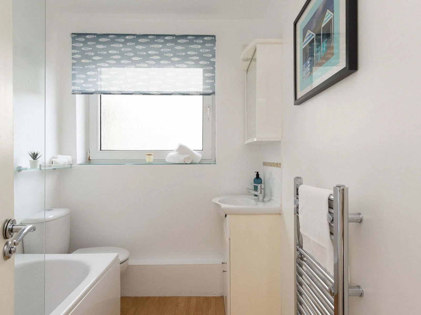 The full family bathroom has a bath with an overhead shower, WC and sink.