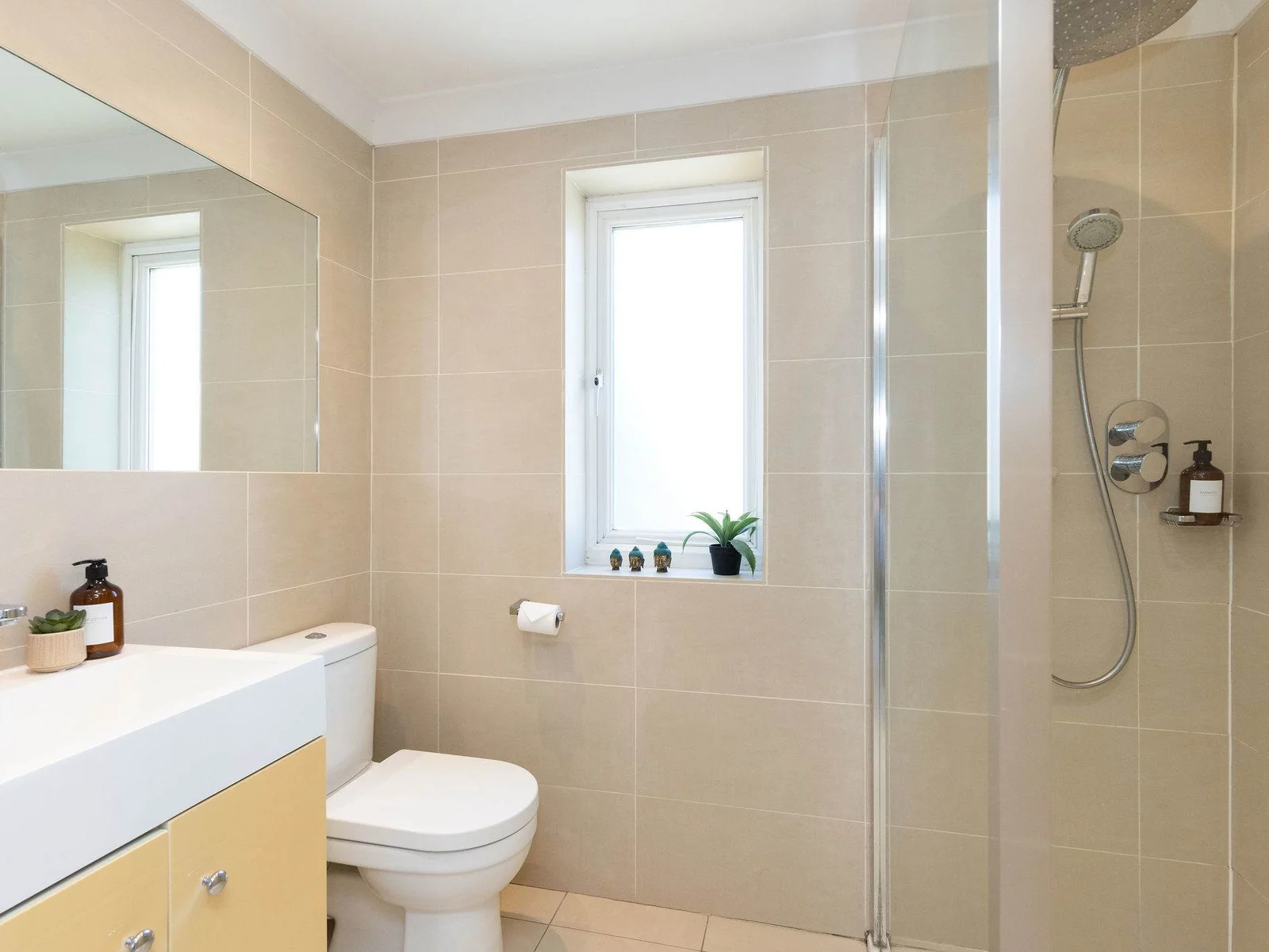 Clean-lined and contemporary, this spacious shower room pairs warm neutral tiling with a large walk-in shower, generous vanity unit and plenty of natural light.