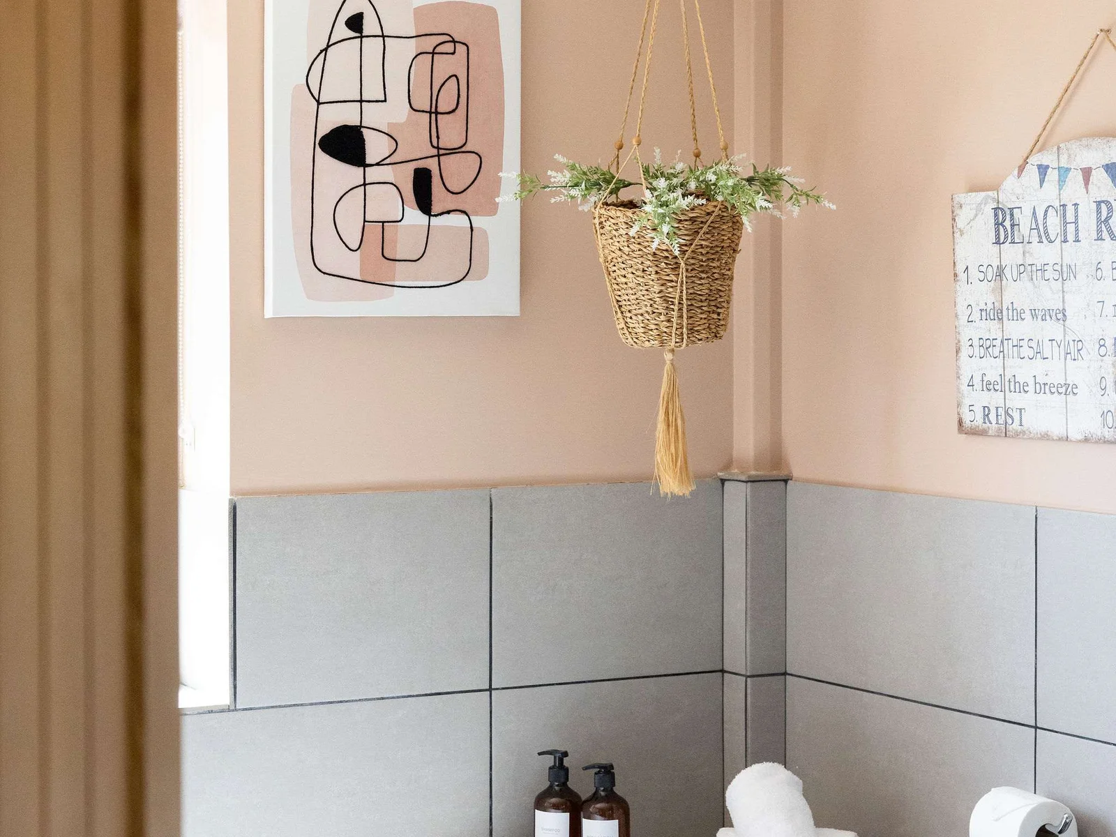 It’s the little details that make this shower room stand out — from the hanging woven basket and soft greenery to the blush walls, dark vanity and neatly styled essentials.