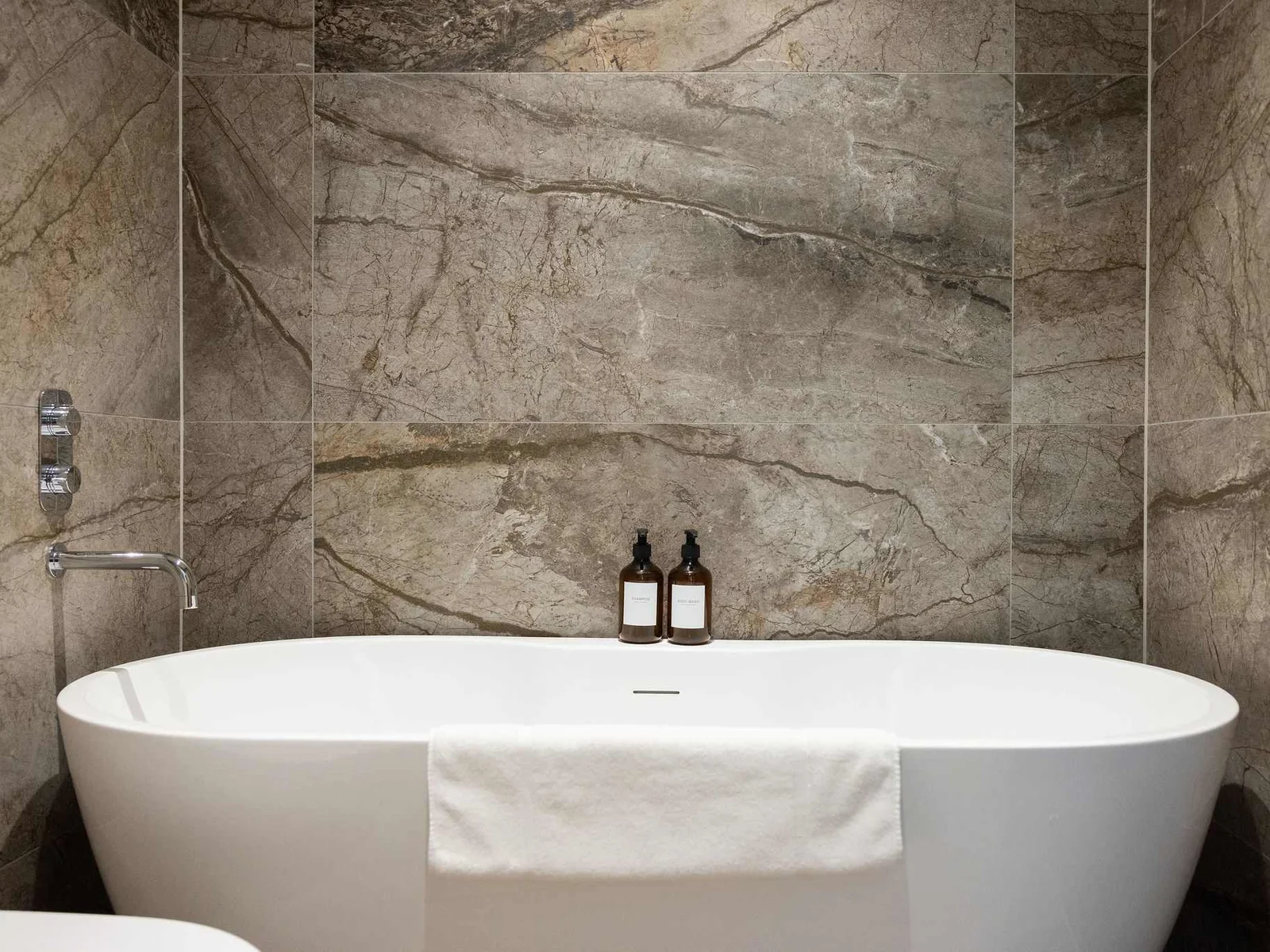 Freestanding bath with stylish stone-effect walls