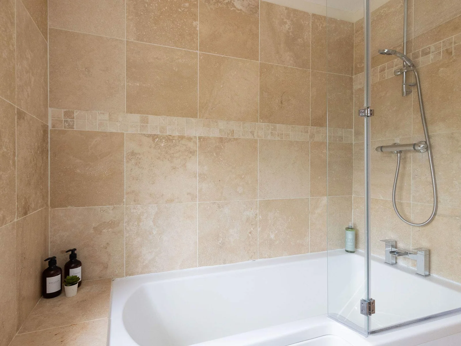 The family bathroom combines a generous bath with an overhead shower, making it a practical and easy space for families getting ready for the day.