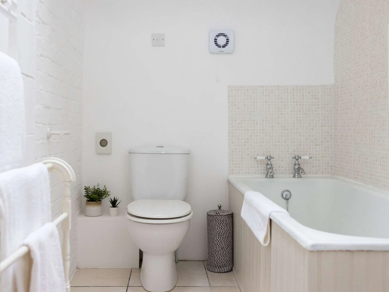 Family bathroom with bath, overhead shower, and fresh towels, perfect for a relaxing soak after a day out.