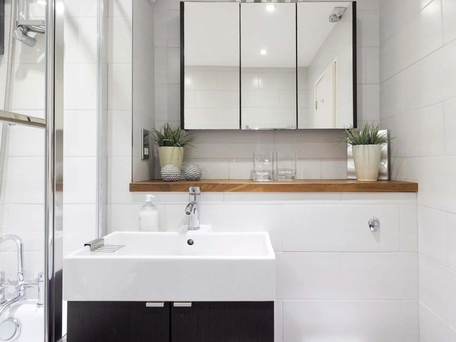 Bright and modern white-tiled bathroom with a sleek overhead mirror for the perfect start to your day.