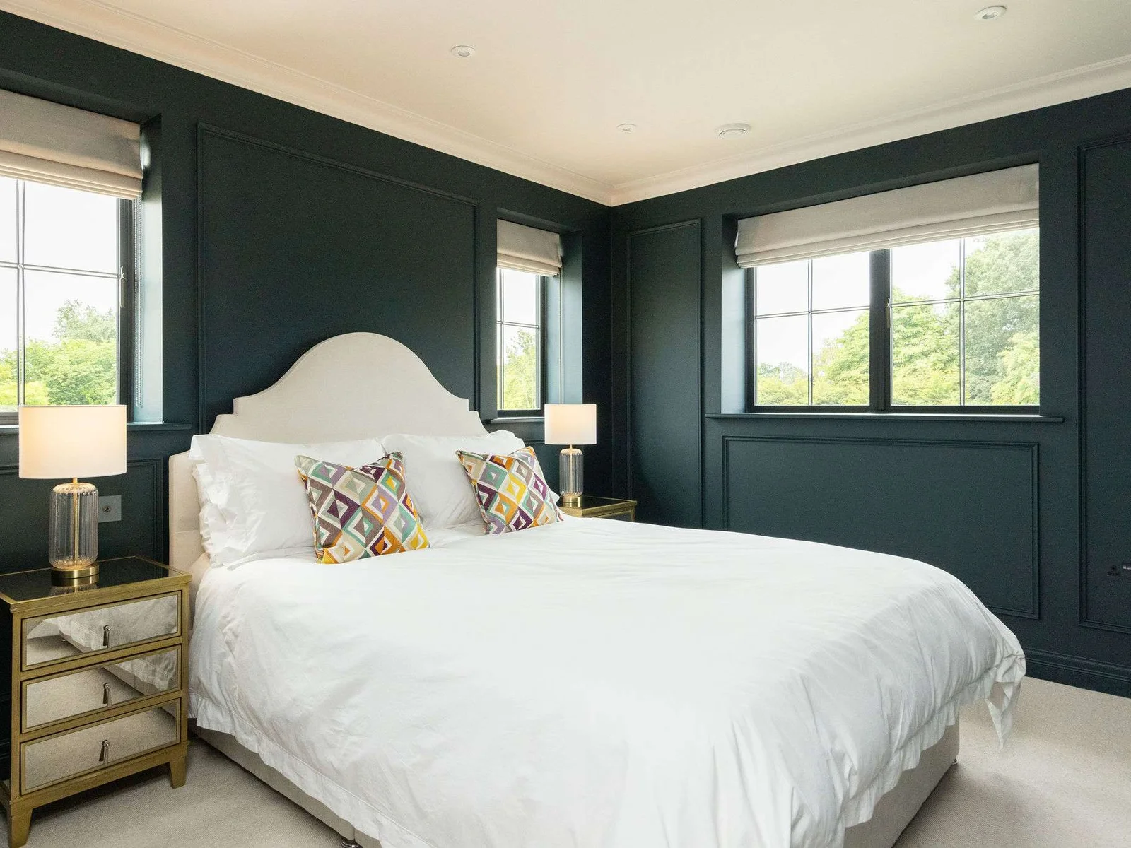 Striking king bedroom with bold dark walls and triple aspect windows