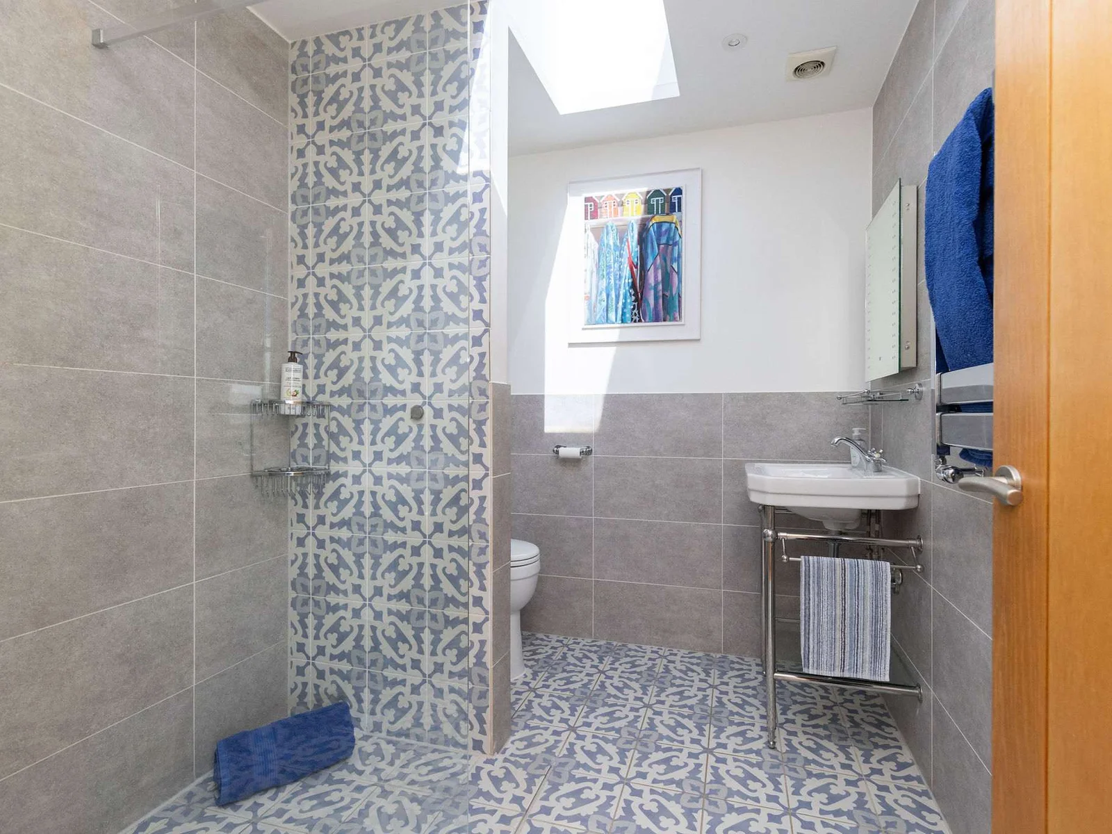 Beautifully tiled bathroom with walk in shower, WC and sink.
