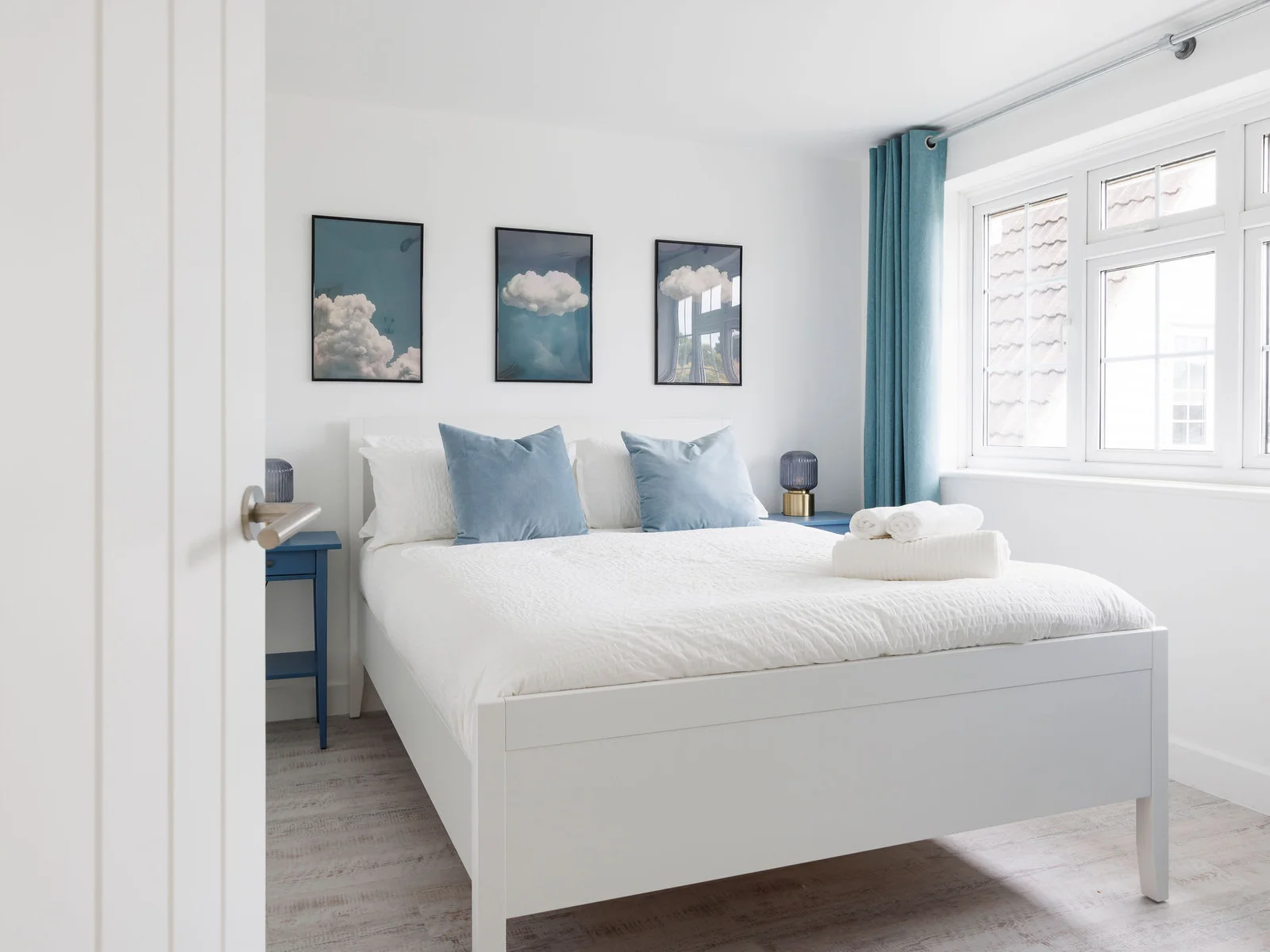 Serene bedroom with cloud-themed wall art and soft blue accents for a dreamy atmosphere