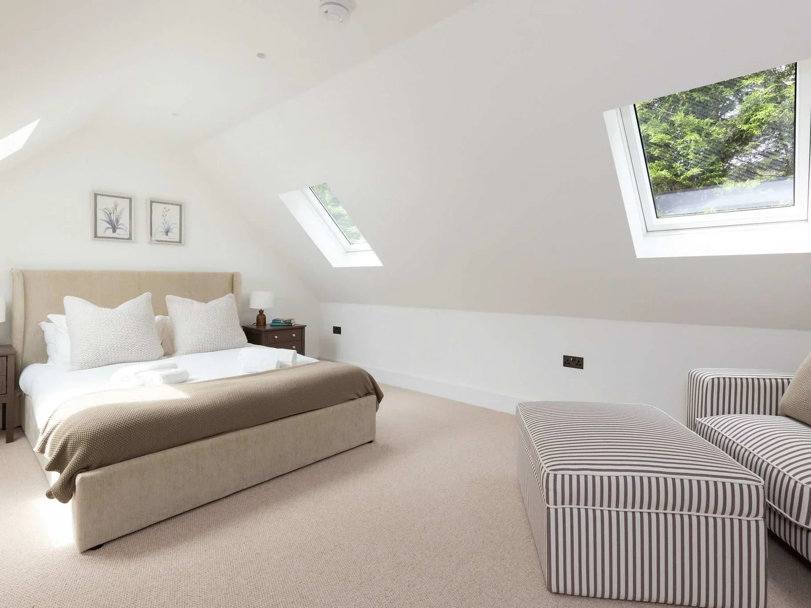 Spacious bedroom with skylights and a comfortable seating area