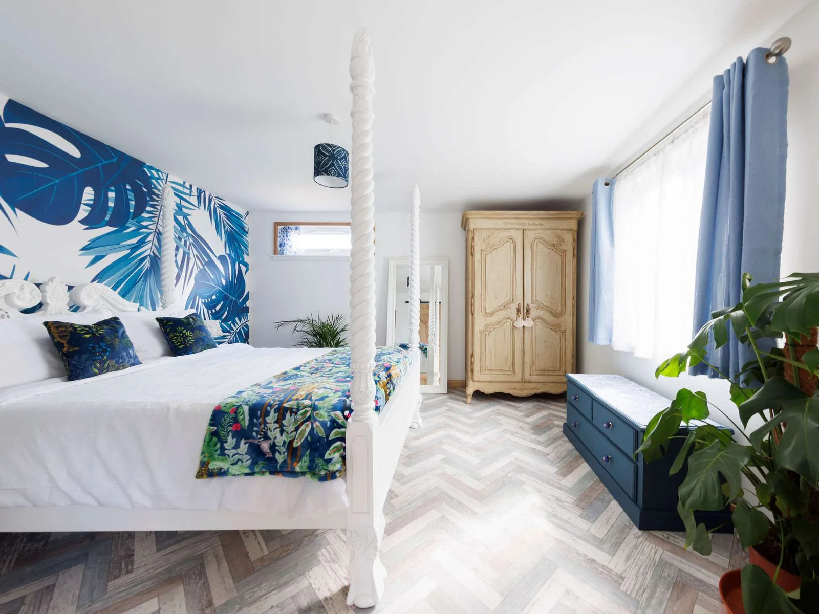 When night falls, retreat to the stylish king bedroom, beautifully decorated with vibrant wallpaper, cushions, throws and house plants.