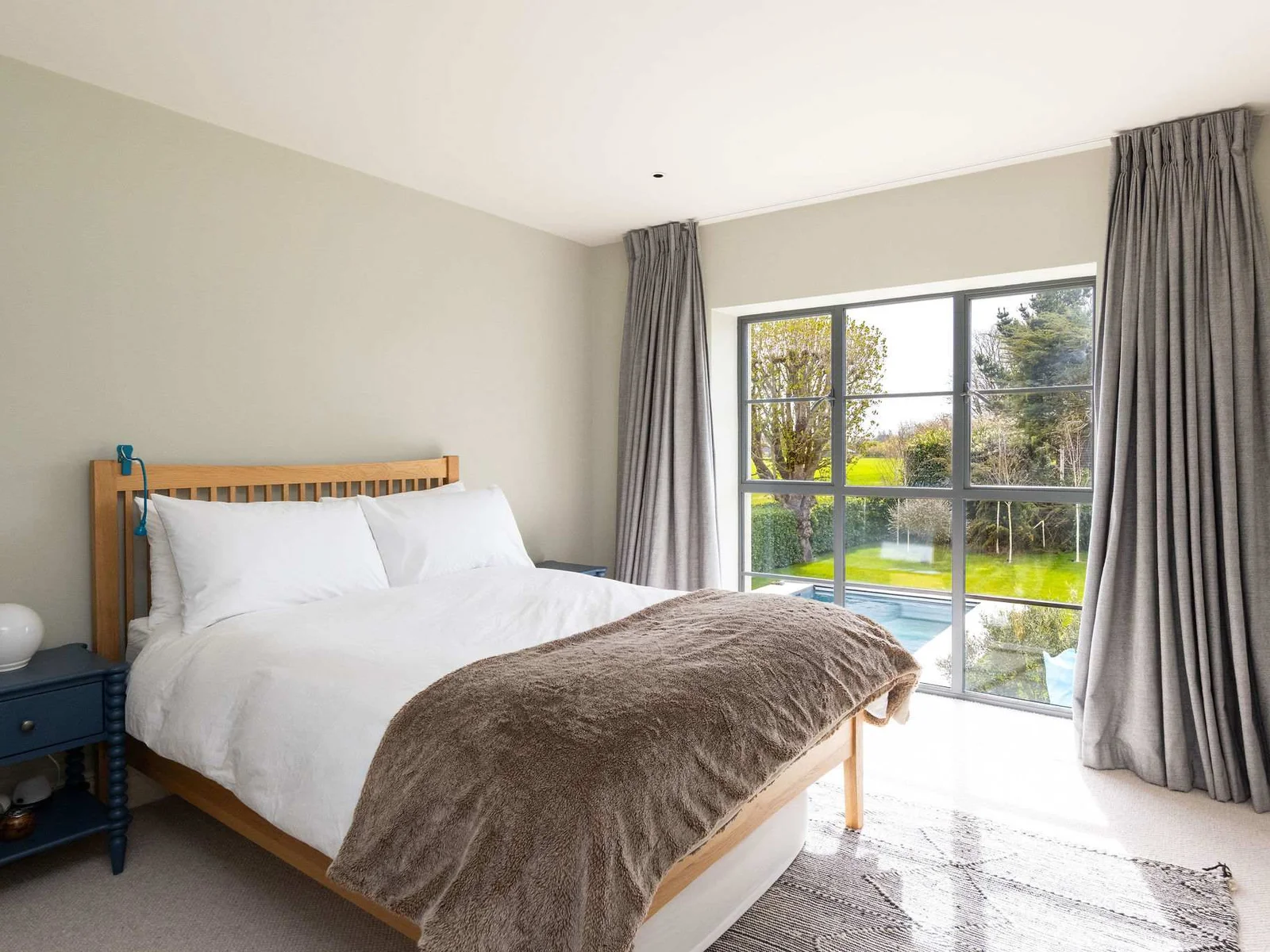 Stylish double bedroom with garden access, cosy textures, and a calm, contemporary feel.