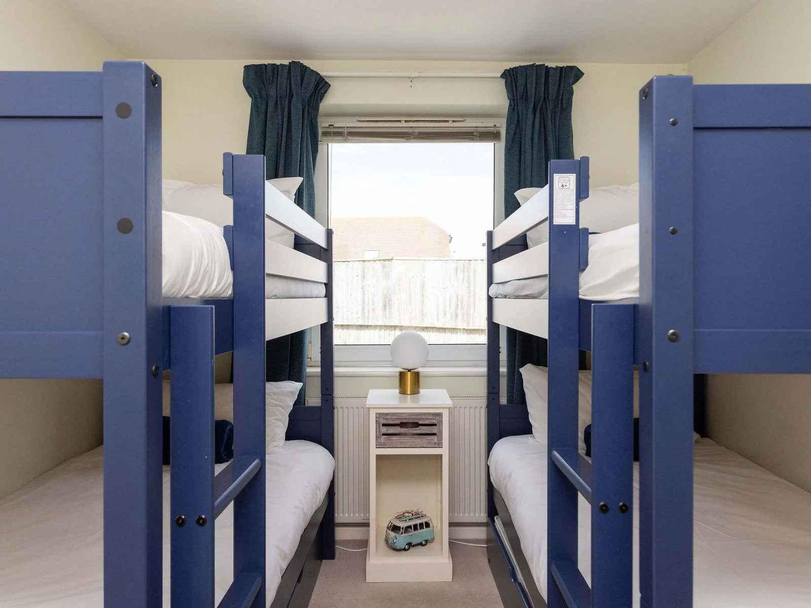 Kids' bunk room with four beds and playful decor