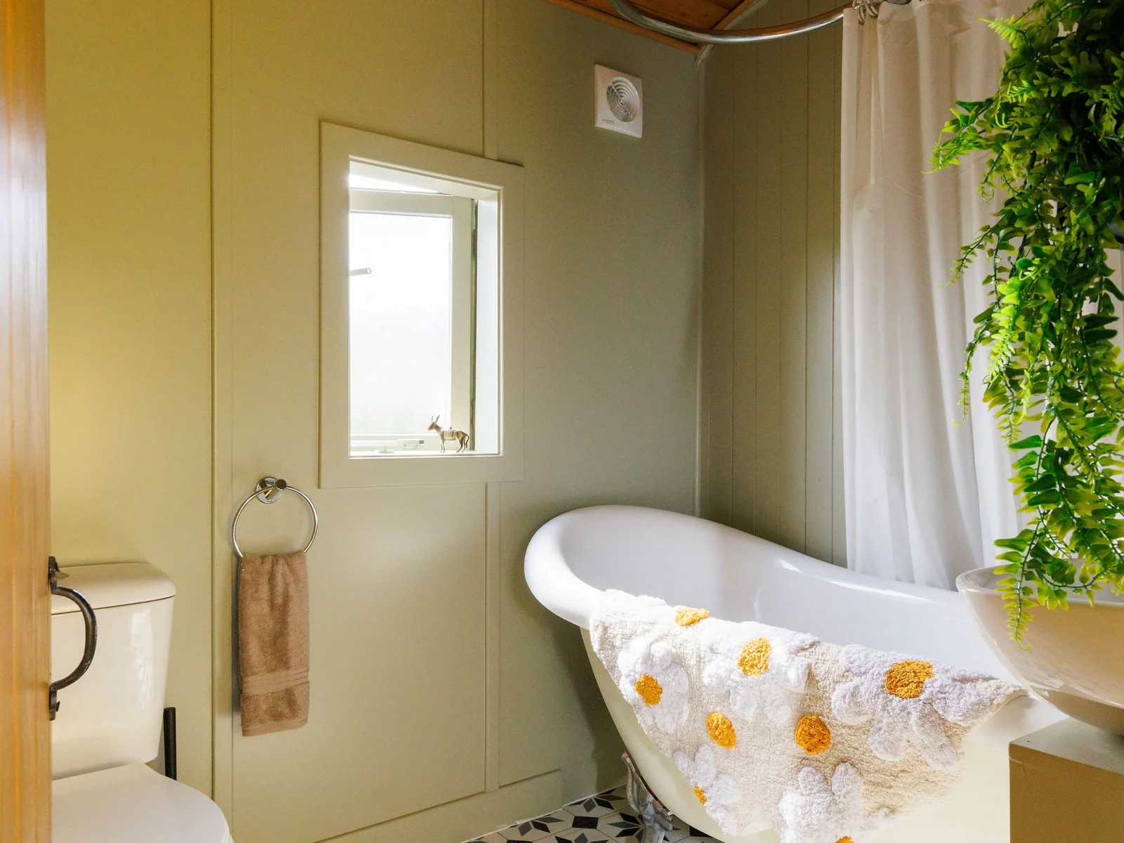 The bathroom has a roll top bath, overhead shower, WC and sink.