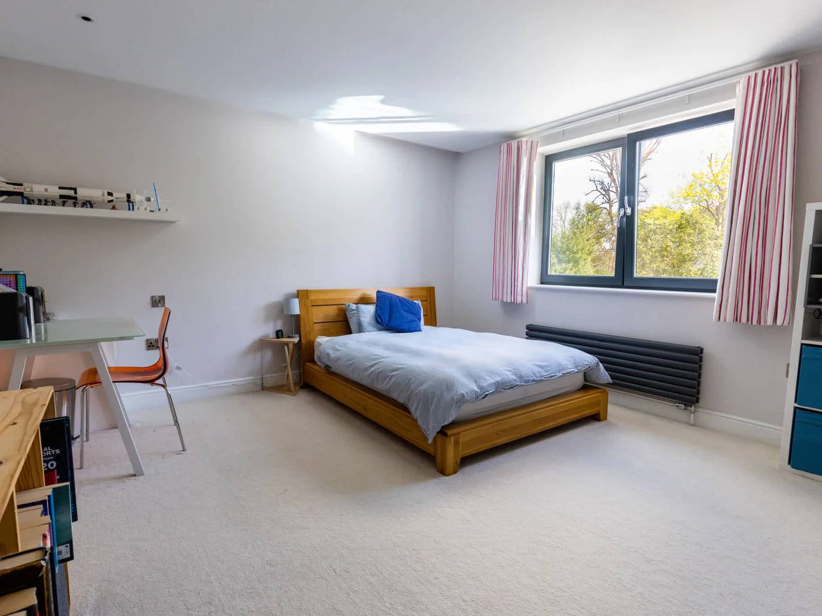 Spacious, light-filled bedroom with comfortable bed, workspace and large window for natural light.