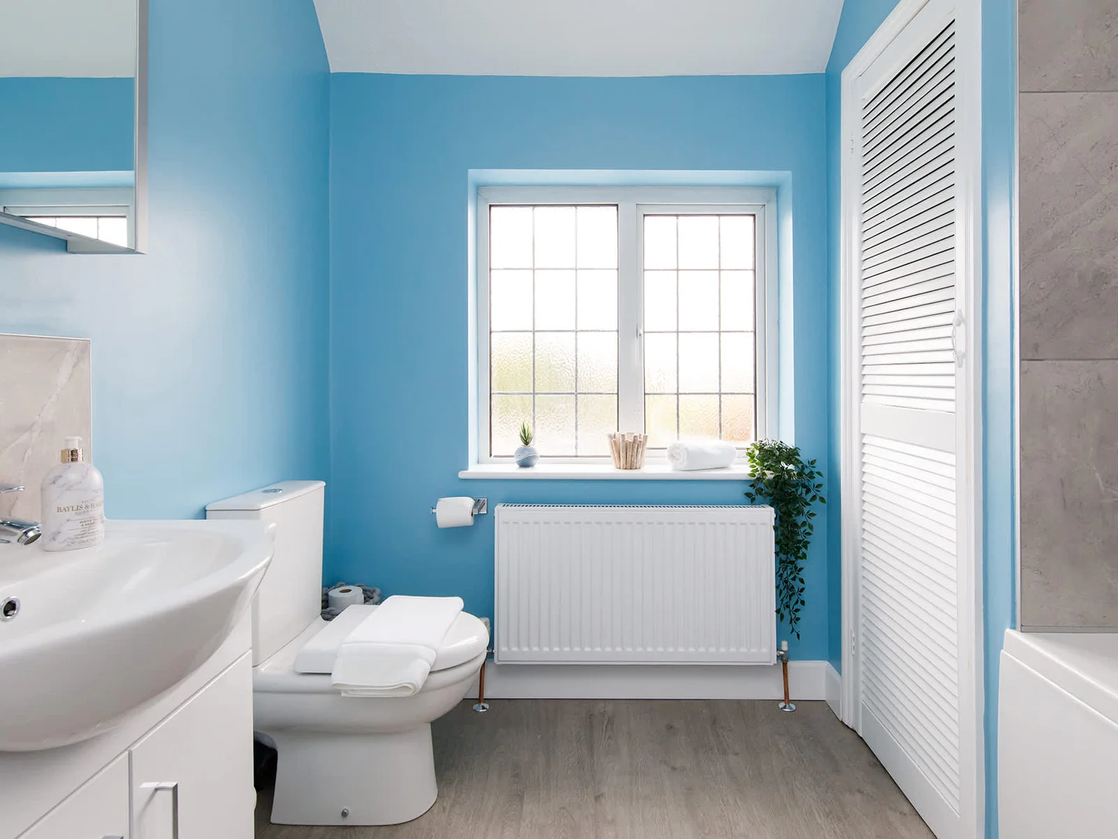 The large family bathroom has a bath with overhead shower, WC and sink.