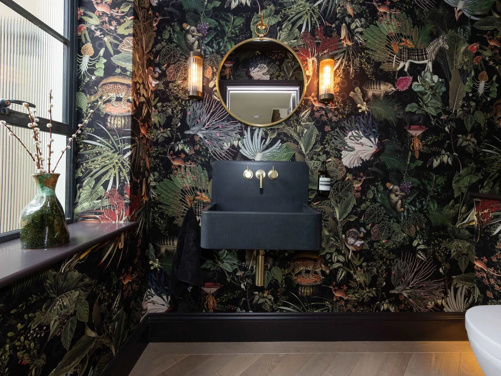 Show-stopping cloakroom featuring dramatic botanical wallpaper, gold accents, and bold designer flair.