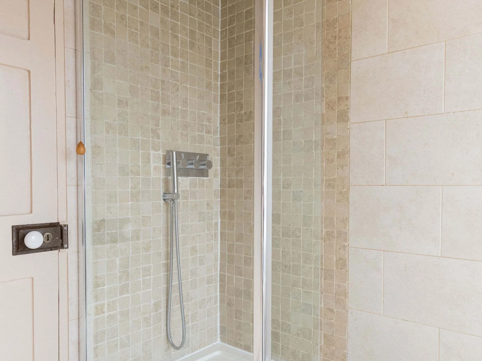 Stylish rainfall shower with soft stone tiles and natural light