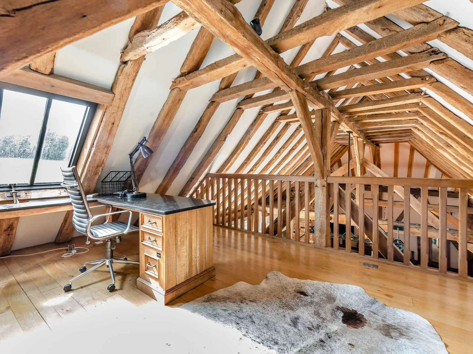 A light-filled mezzanine workspace tucked beneath the original oak roof timbers.