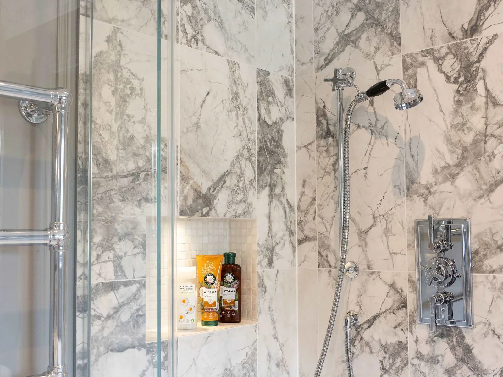 Marble-tiled rainfall shower with luxe fixtures