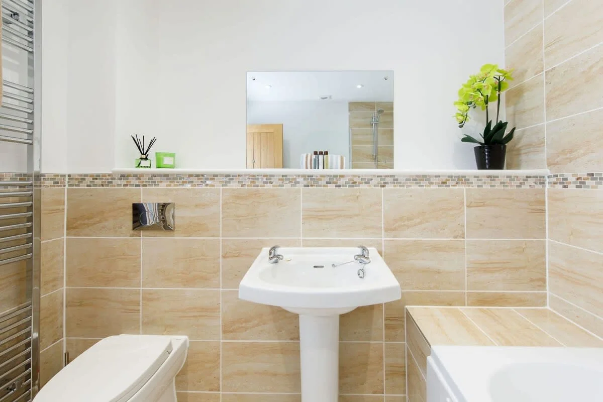 A WC, sink with overhead mirror and bath.