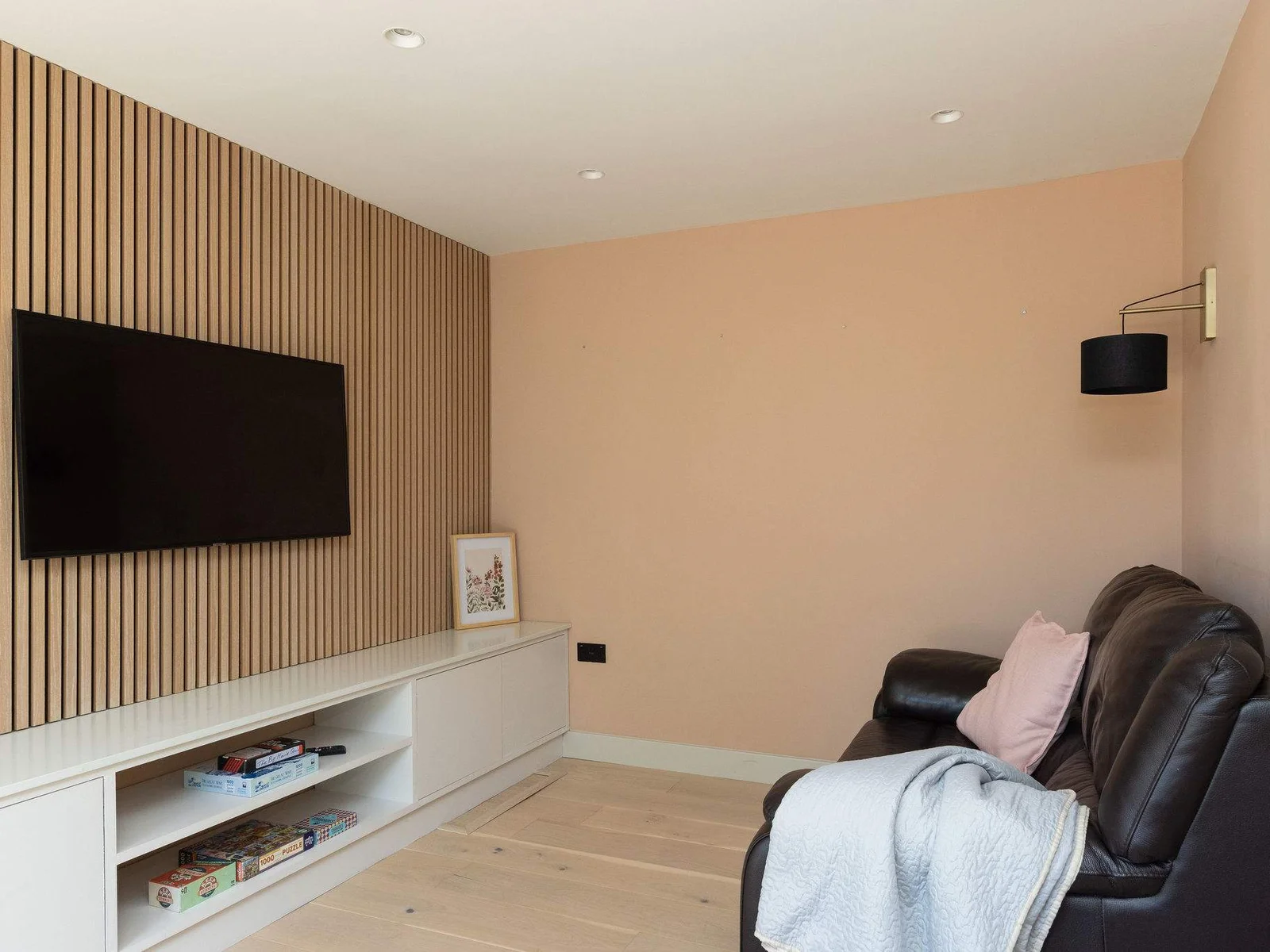 A cosy snug room with a comfy sofa and TV, offering a quieter space to relax, with doors opening directly out to the garden.
