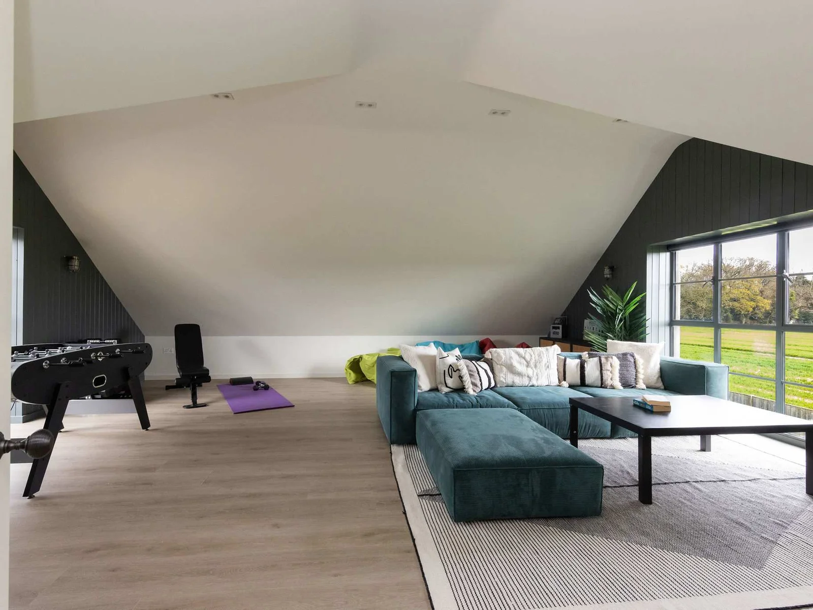 Spacious games room with foosball, comfy seating, and garden views — ideal for unwinding together.