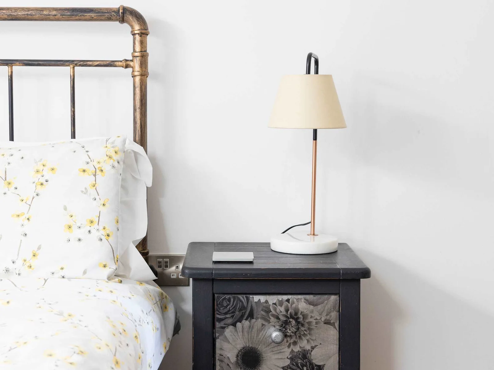 Comfortable bed with chic side table and lamp.