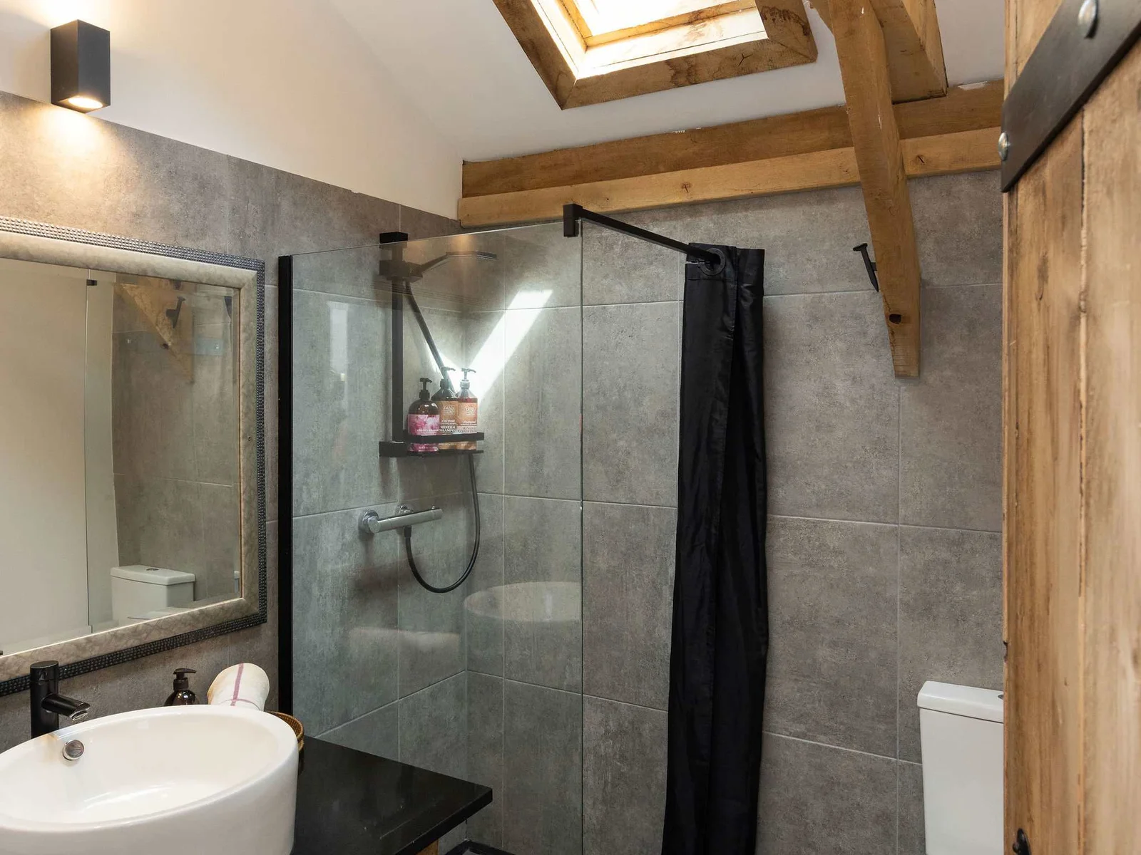 Refresh yourself in this stunning modern bathroom featuring a walk-in shower and bright skylight.