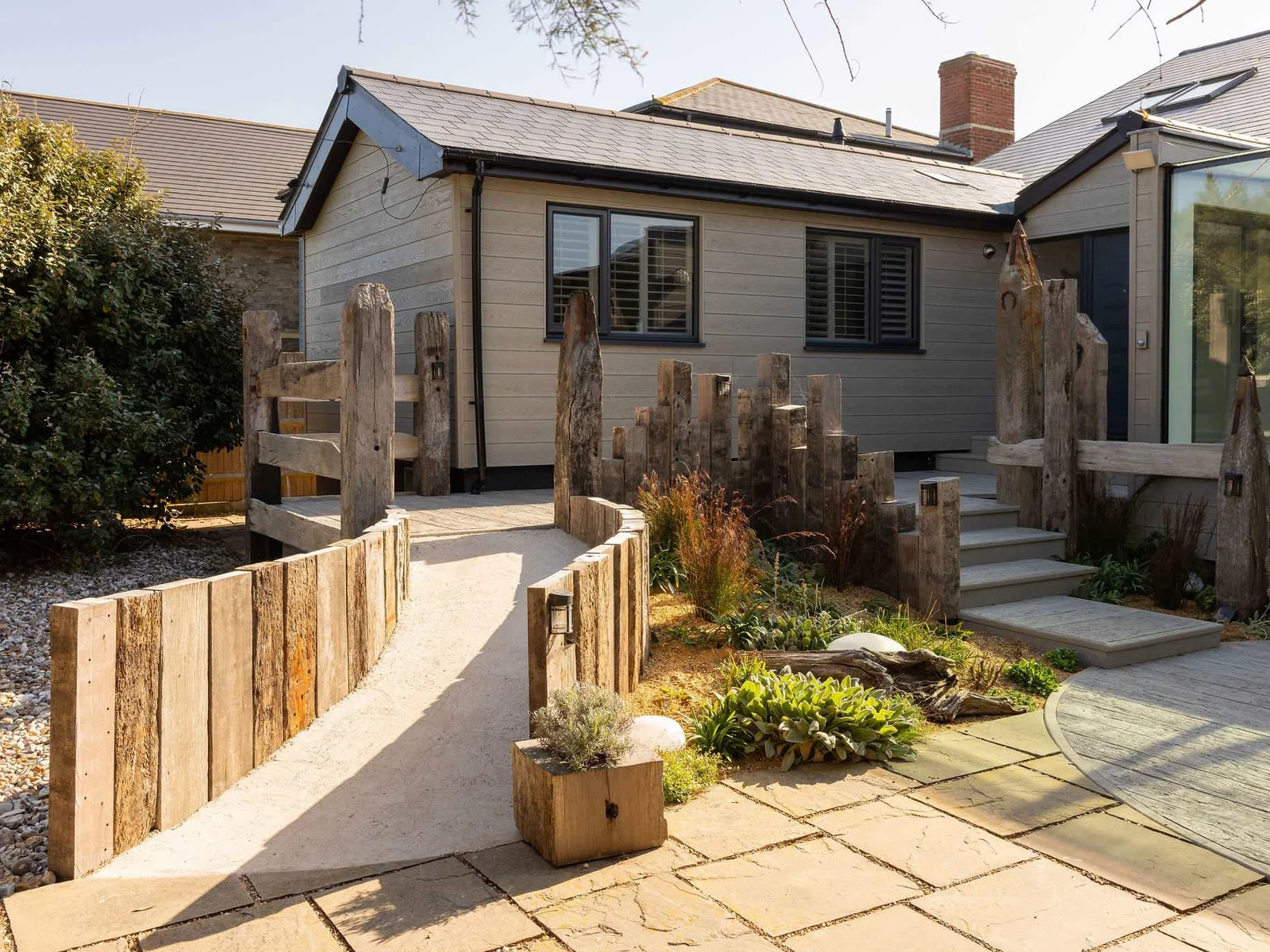 Landscaped front entrance with sleepers and planters.