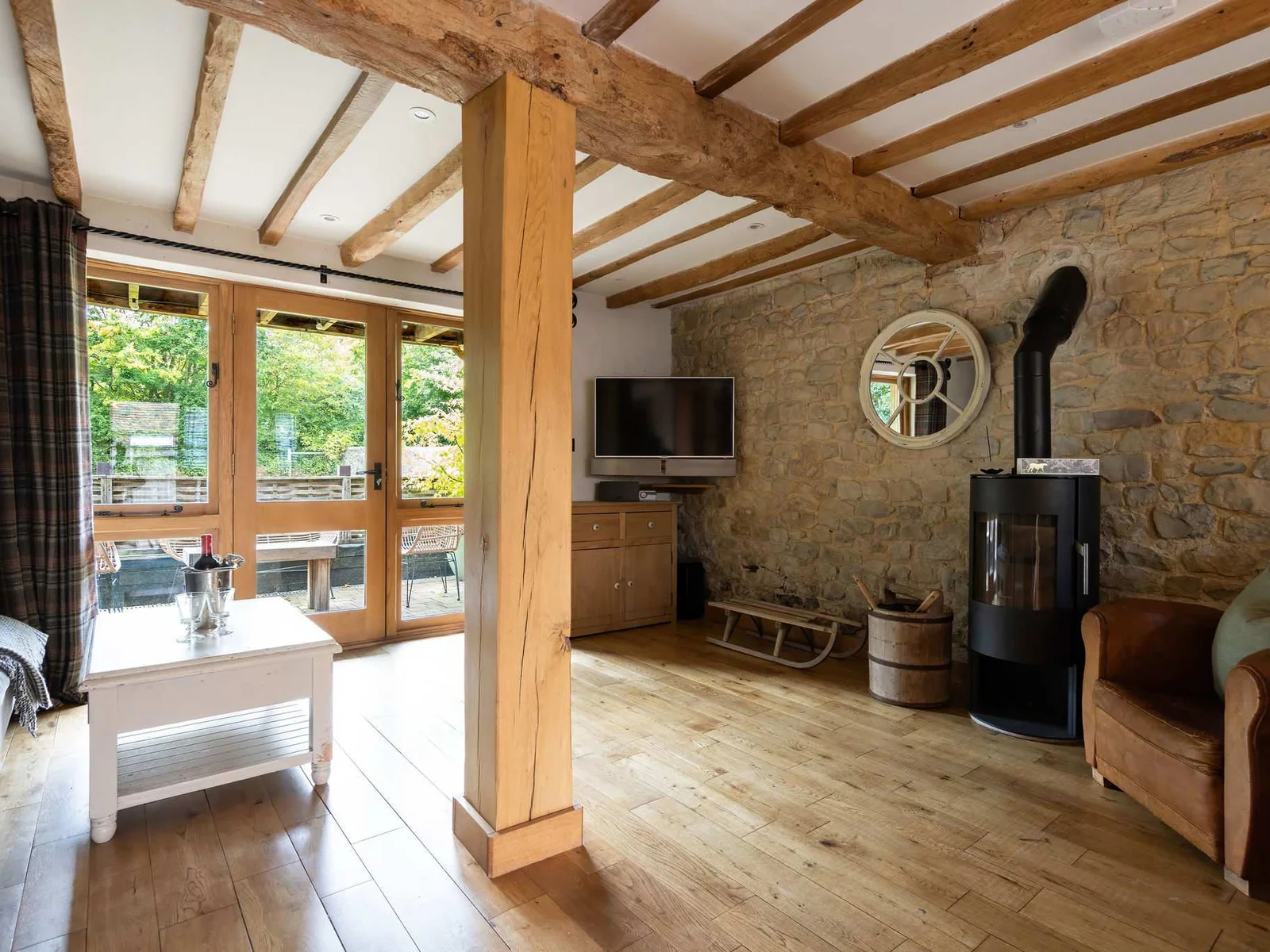 A cosy lounge with exposed stone, a wood-burning stove, and doors opening to the terrace