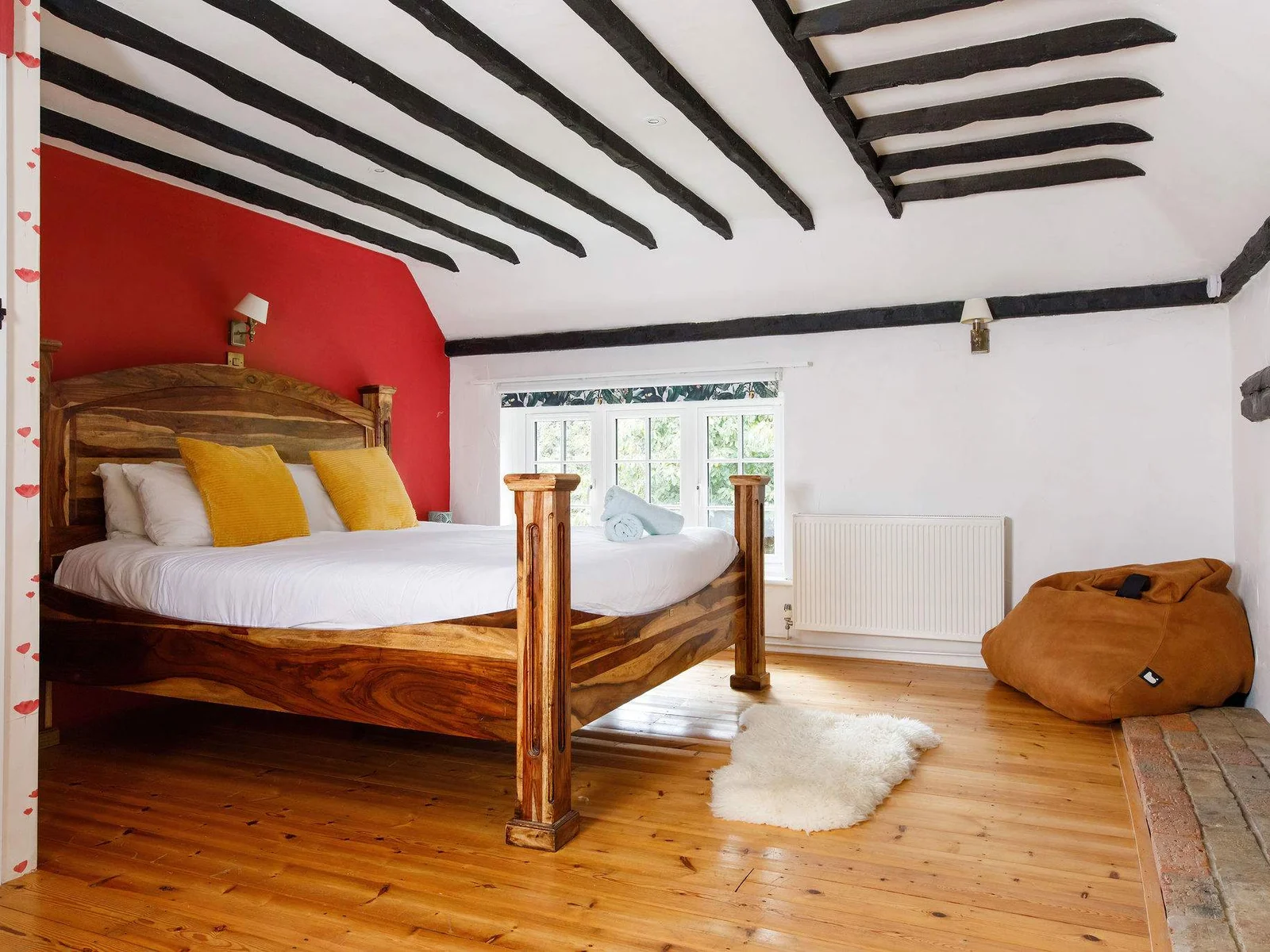This master bedroom has many original features, such as a fireplace, wooden beams and flooring.