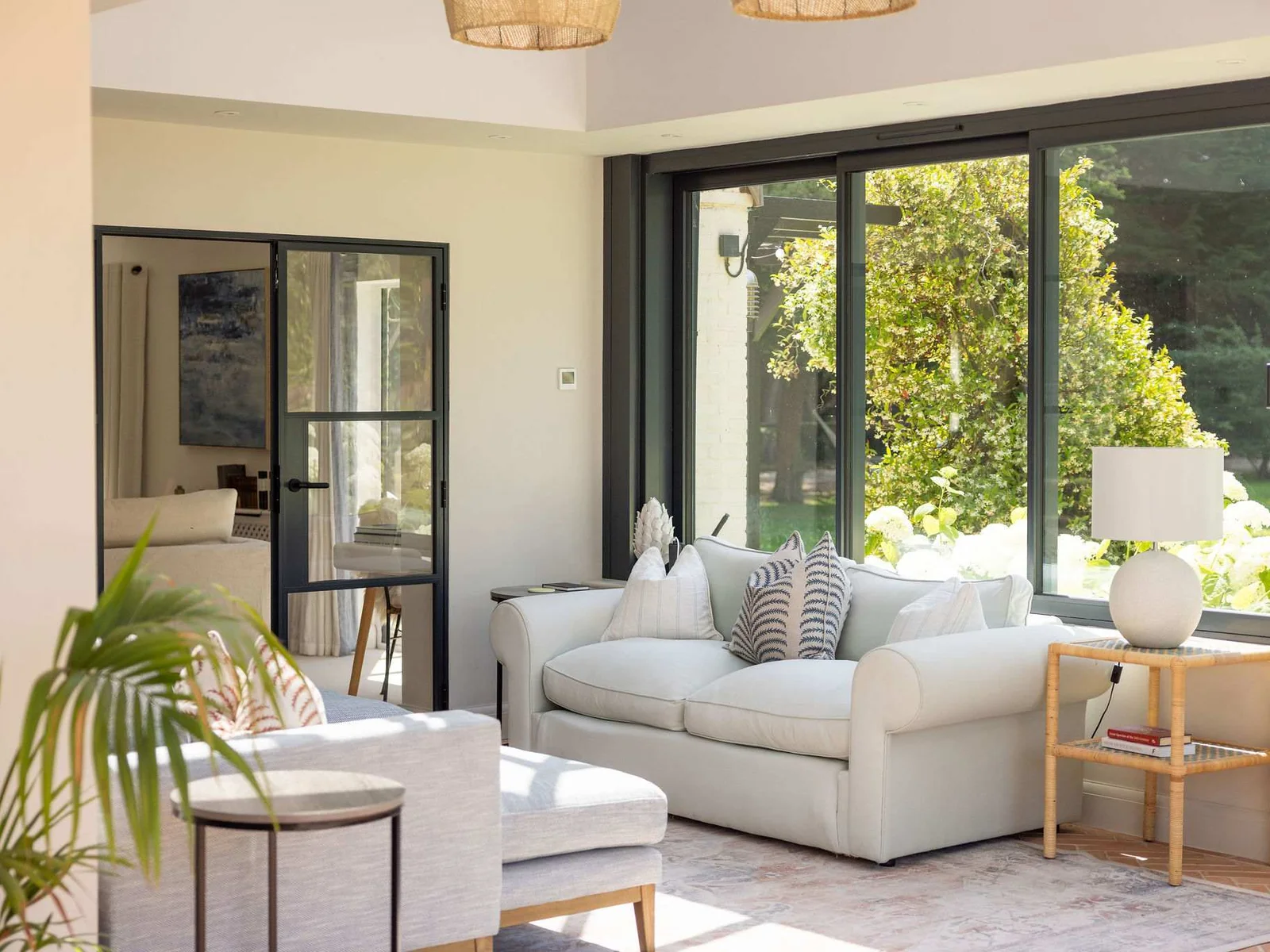 Inviting lounge corner with cosy armchairs and peaceful garden views through expansive windows