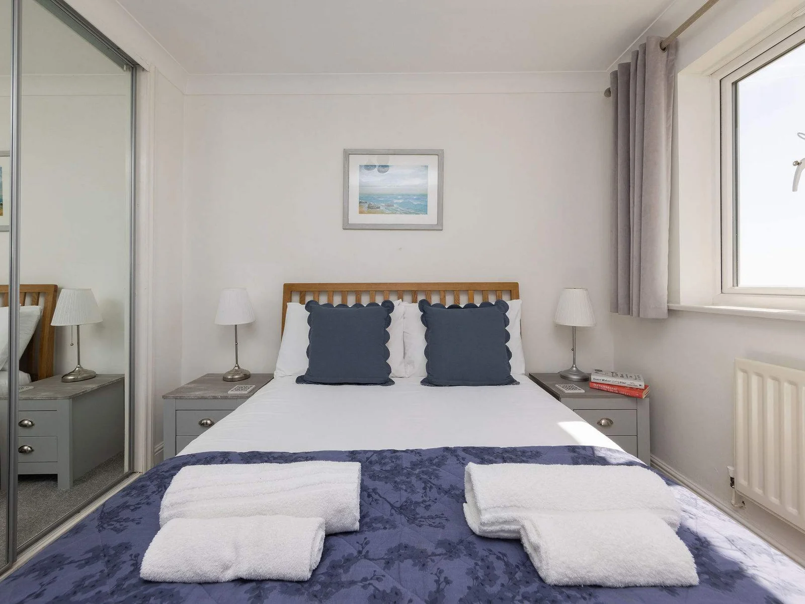 Comfortable and stylish bedroom with mirrored wardrobes, perfect for a restful seaside getaway.