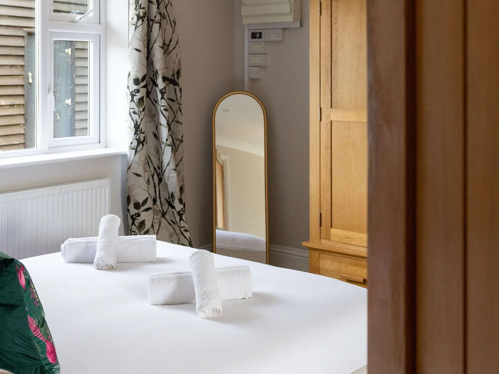 A peaceful ground-floor double bedroom with crisp white linen and soft, neutral styling — a comfortable and convenient retreat with its own en-suite bathroom.